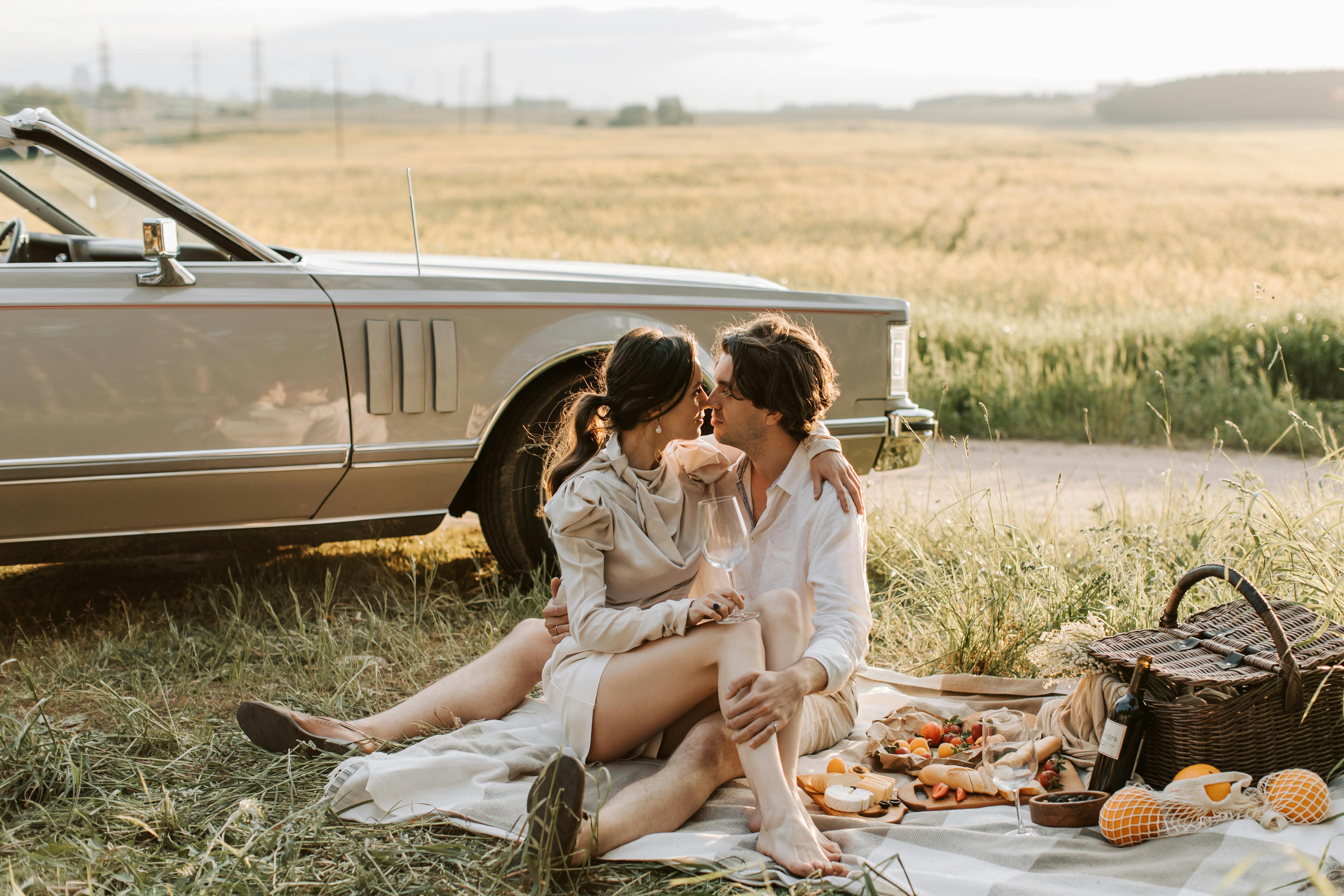 a romantic couple sitting on a grassy field