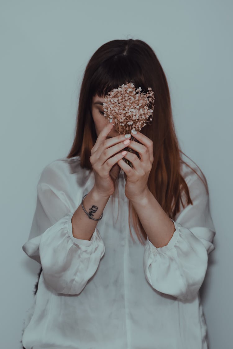 Woman With Long Hair Hiding Face Behind Bouquet Of Flowers