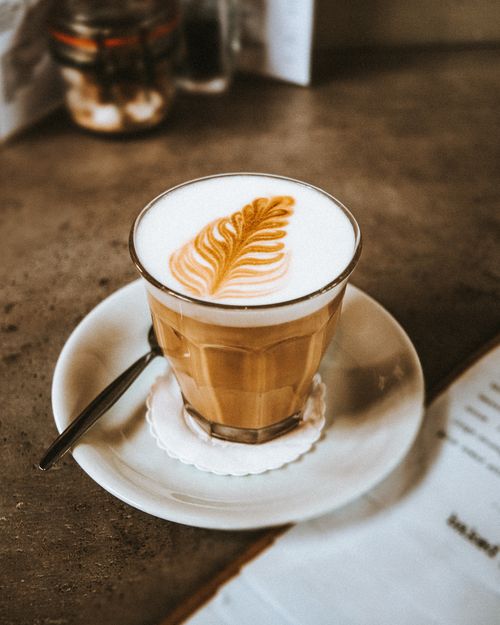 Free A beautifully crafted cappuccino with latte art in a cozy cafe setting. Stock Photo