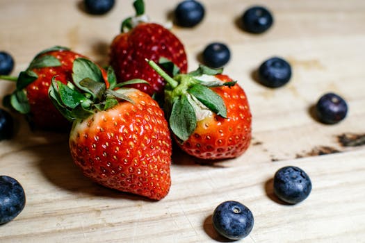 Close-up of ripe strawberries and blueberries on a wooden table, perfect for healthy eating concepts.