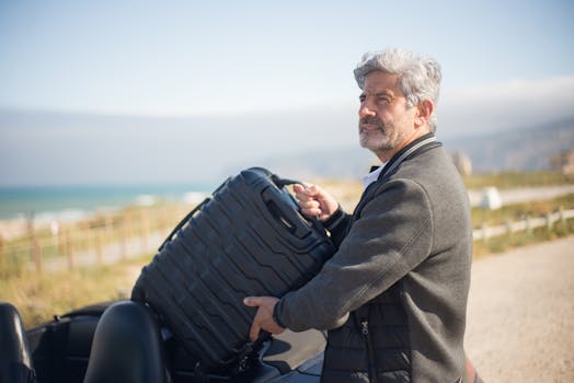 Elderly man with suitcase by a convertible on a scenic coastal journey in Portugal.