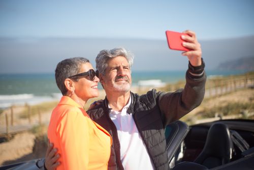 Free Smiling couple taking a selfie by the beach in Portugal on a sunny day. Stock Photo