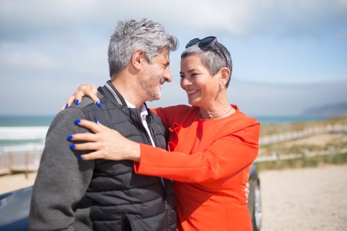 Free Happy couple embracing by the beach in Portugal, feeling the love and joy under sunny skies. Stock Photo