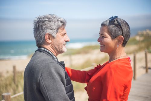 Free Mature couple smiling lovingly at each other on a sunny beach in Portugal. Stock Photo