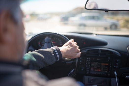 Adult man driving a car with focus on dashboard and steering, capturing the essence of travel.