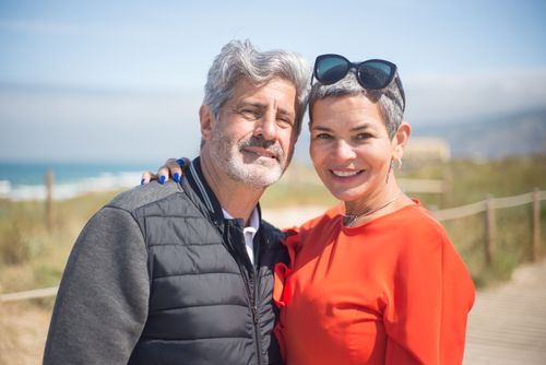 Free A joyful senior couple smiling together at a sunny beach in Portugal. Stock Photo