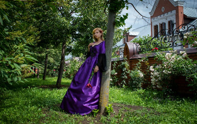 A Woman In A Princess Gown Leaning On A Tree