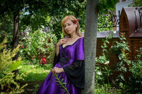 Free A woman in a purple dress posing elegantly in a lush garden atmosphere. Stock Photo