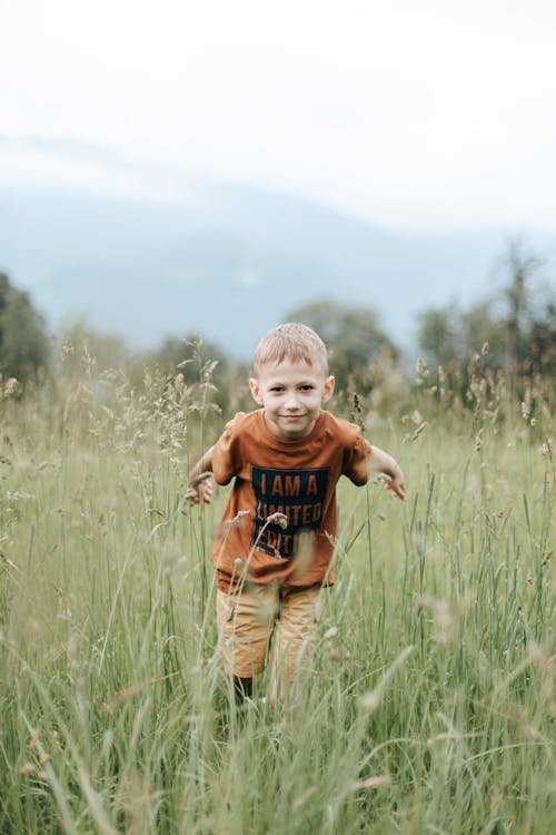 A Boy Standing on the Grass Field
