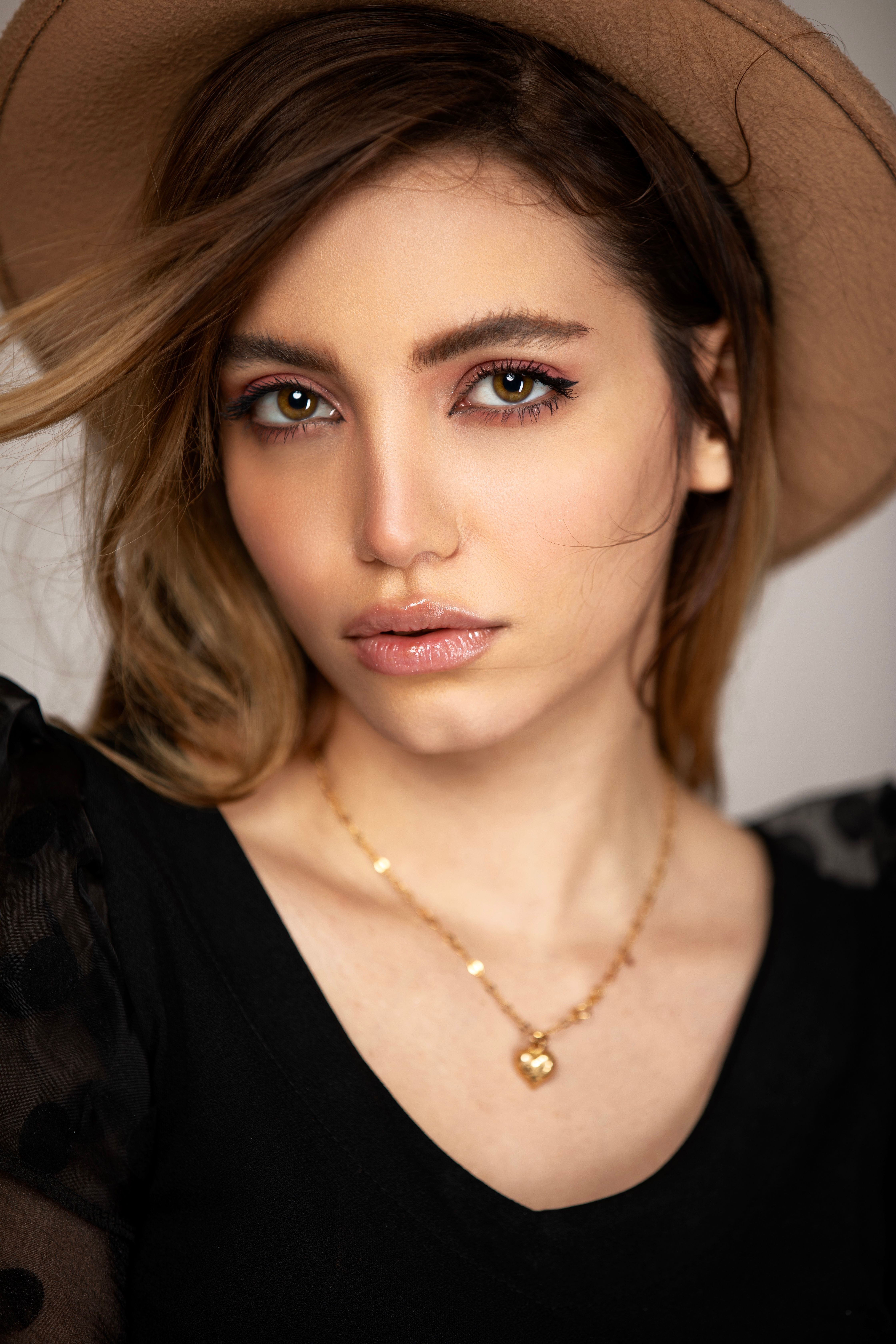 Close-up portrait of a woman in a black top and hat, exuding elegance and style.