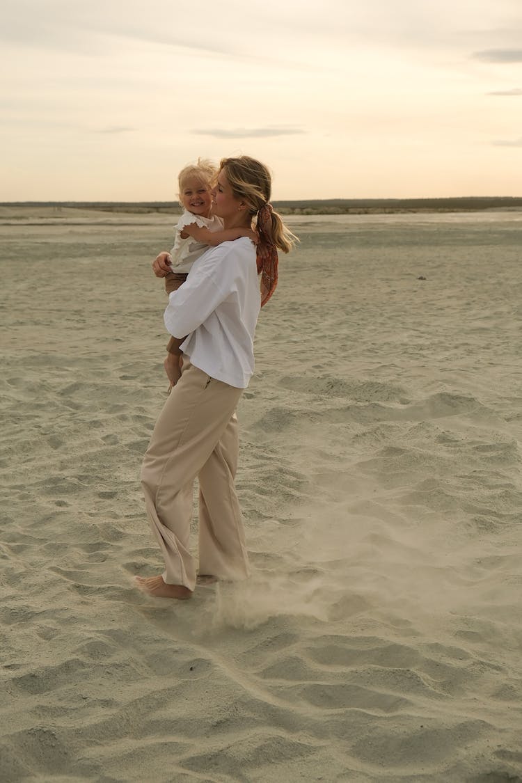 Mother Holding Her Little Baby On The Beach 