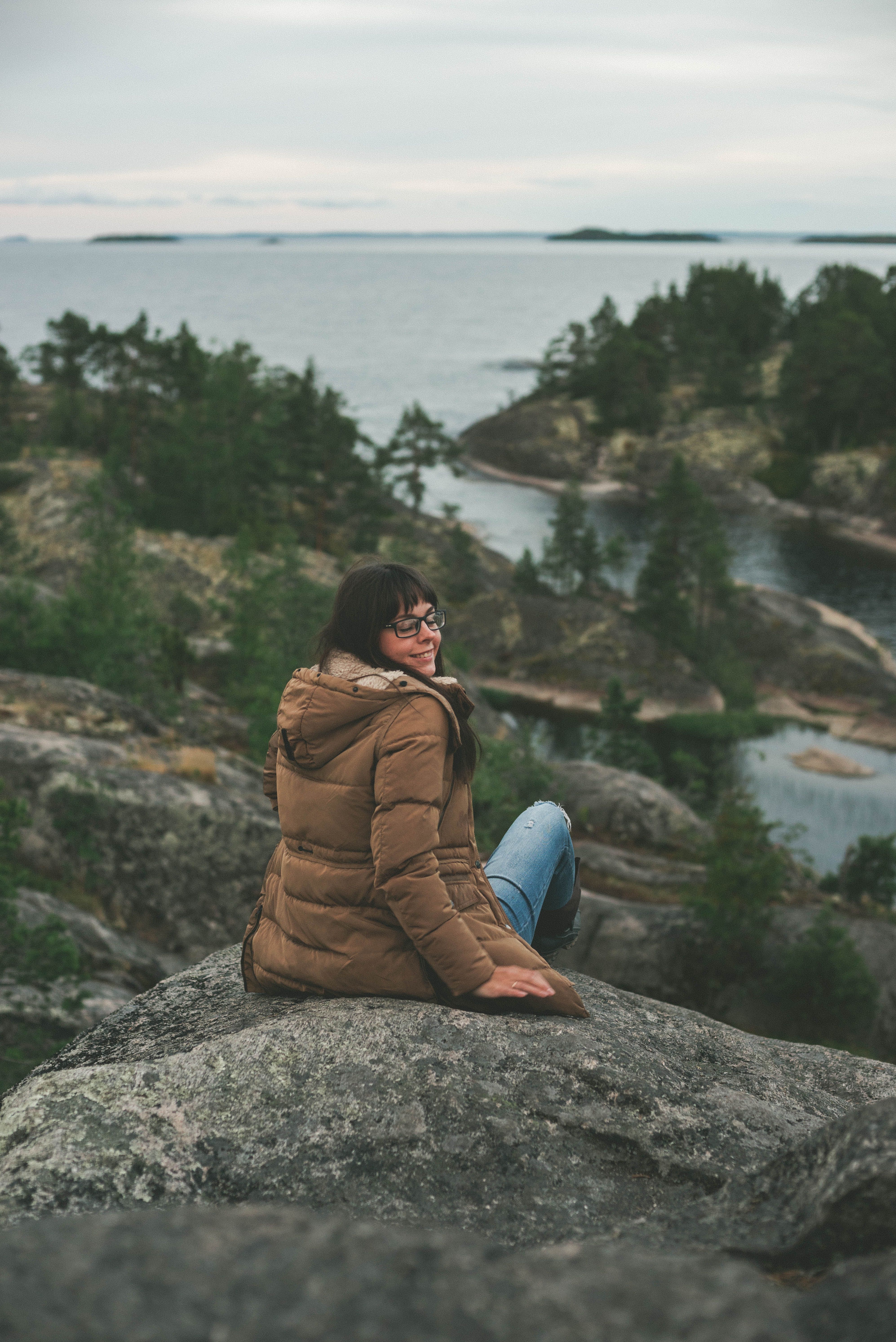 Woman sits on rocks enjoying scenic view in Karelia, Russia.