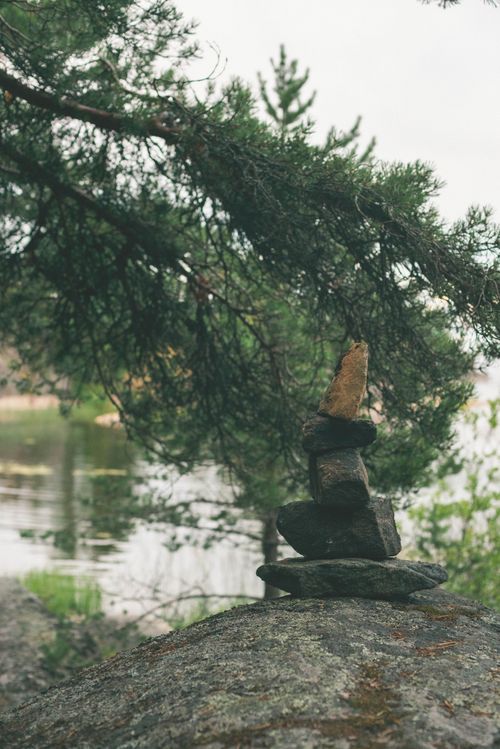Free Stacked stones and pine branches by a tranquil lake in Karelia, Russia. Stock Photo
