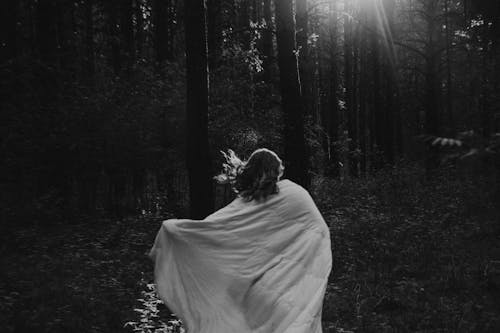 Woman Covered in White Textile Standing in the Forest