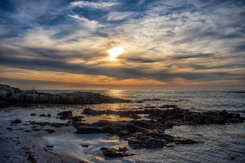 Free Stunning sunset over a rocky shore in Nordland, Norway, reflecting vibrant colors on the sea. Stock Photo