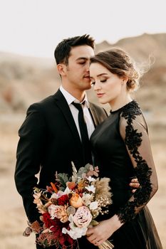 A stylish couple in an elegant embrace during an outdoor wedding shoot.
