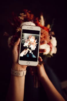 Close-up of a smartphone showing a floral bouquet image, held by a person.