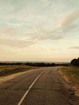 Peaceful countryside road stretches into the horizon under a pastel sky in Mazyrski rajon, Belarus.