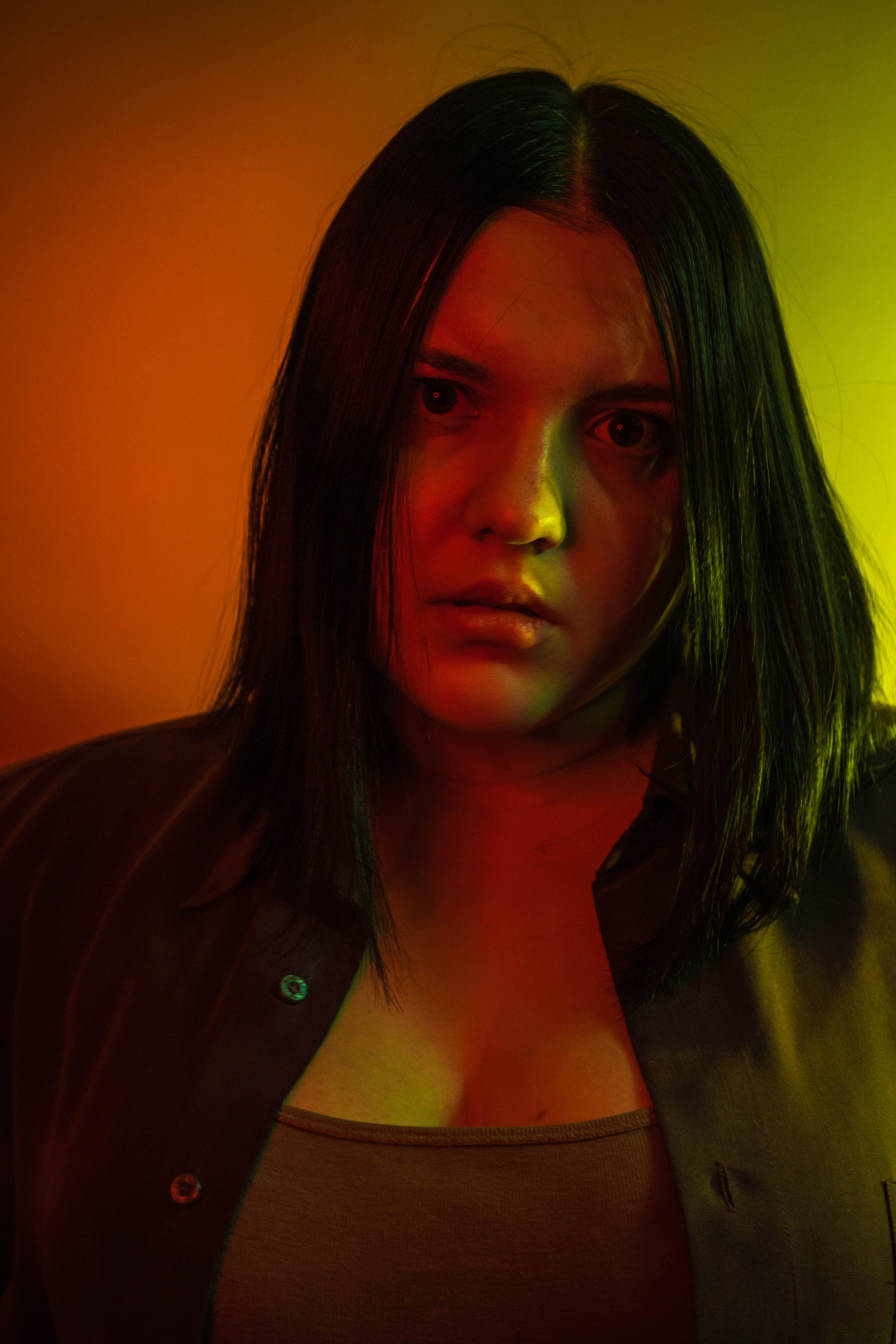 Moody portrait of a woman with vibrant red and green lighting, conveying a dramatic atmosphere.