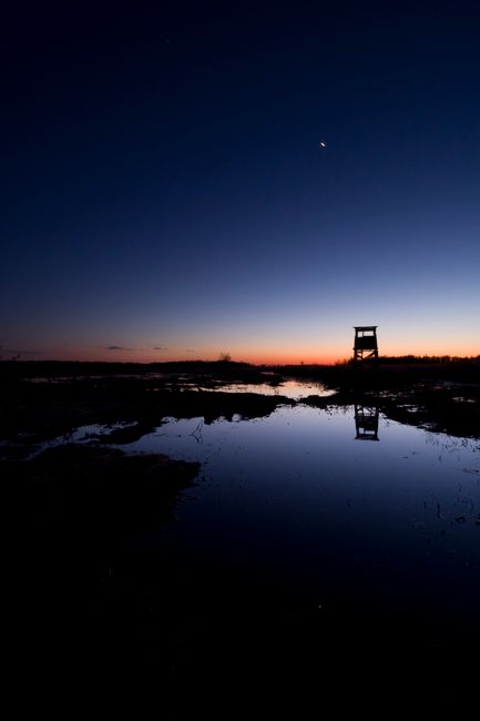Stunning twilight landscape with lake reflection and silhouette observation tower.