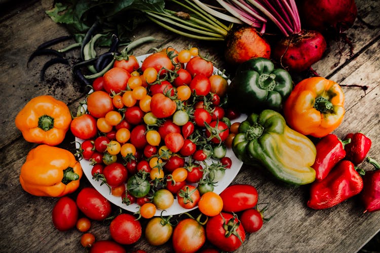 Close-Up Shot Of Tomatoes And Peppers On A Wooden Surface