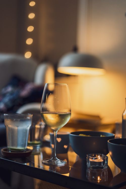 Free Warm and cozy indoor setting with a glass of white wine, candles, and soft lighting. Stock Photo