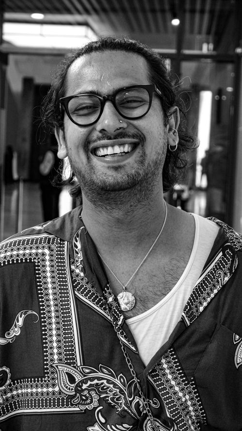 Free Black and white portrait of a smiling man wearing glasses and a printed shirt. Stock Photo