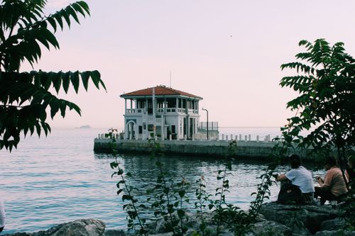 Free Charming waterfront house by seawall, surrounded by ocean and lush foliage. Stock Photo