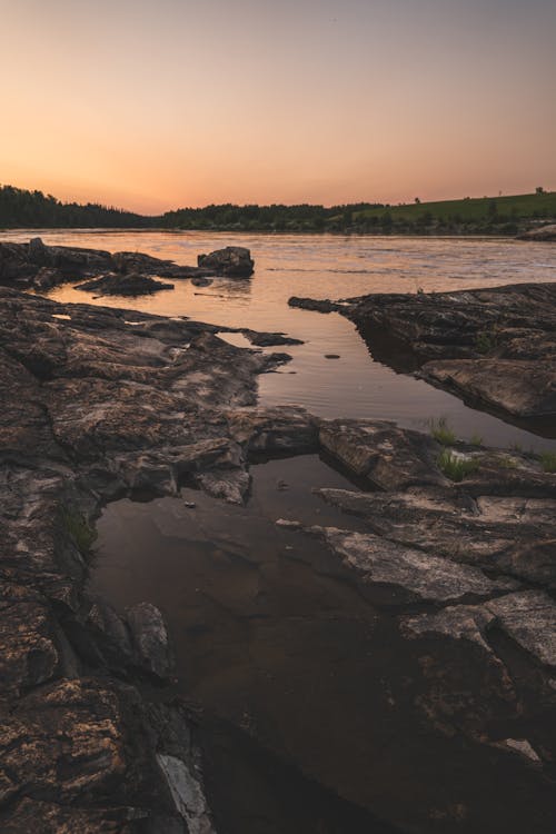 Body of Water Near Rocks during Sunset