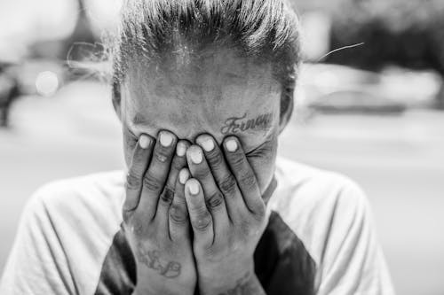 Grayscale Photo of Person Covering Face with Hands