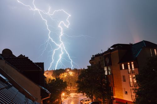 Free Captivating lightning bolt illuminates night sky above urban residential area during a storm. Stock Photo