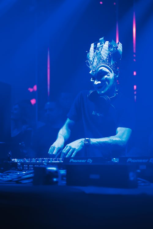 A Dj Wearing a Mask using a Audio Mixer