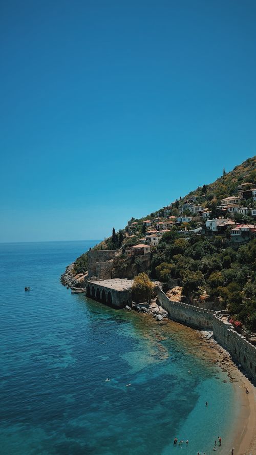 Free Breathtaking view of a Mediterranean coastline with azure waters, featuring hillside houses and rugged cliffs. Stock Photo