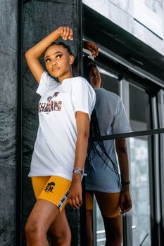 Stylish young woman in cycling shorts posing by a mirror indoors.