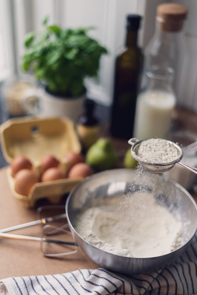 A Person Sifting The Flour