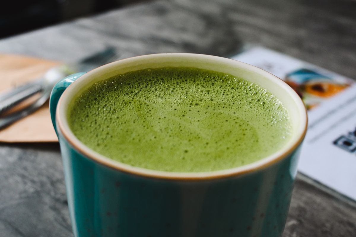 A creamy matcha latte in a green ceramic cup
