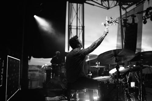 Grayscale Photo of Man Playing Drums on Stage