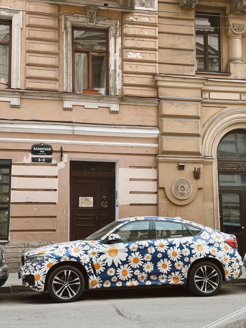 Free Floral-patterned car parked on a historical city street with ornate architecture. Stock Photo