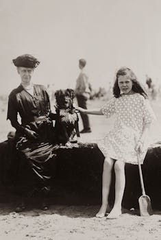 Black and white vintage photo of a woman, a girl, and a dog enjoying a summer day at the beach.