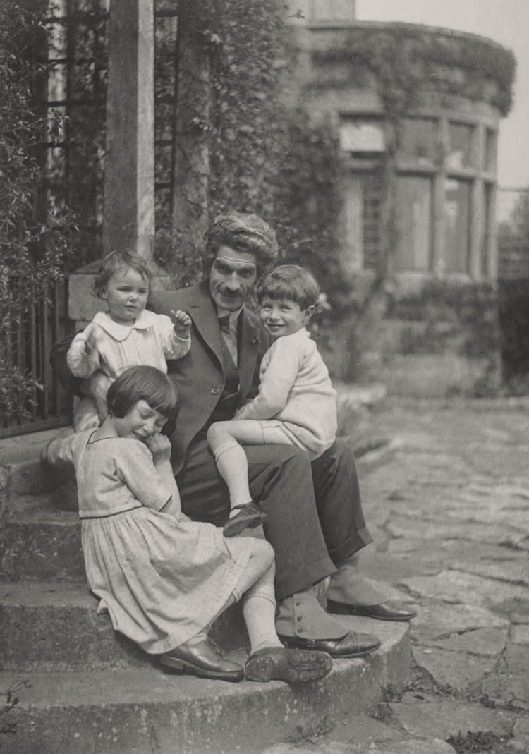 Grayscale Photo Of Family Sitting On Concrete Steps