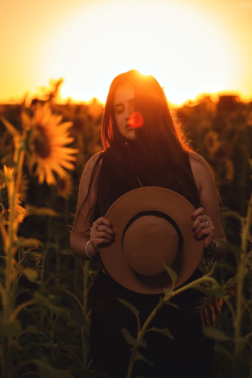 Woman Standing on Sunflower Field during Sunset