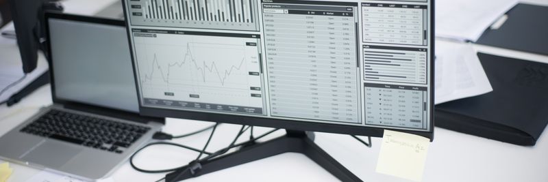 A professional workspace featuring computers and analytical graphs on a monitor, symbolizing modern business environment.
