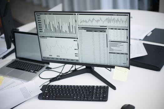 A professional workspace featuring computers and analytical graphs on a monitor, symbolizing modern business environment.