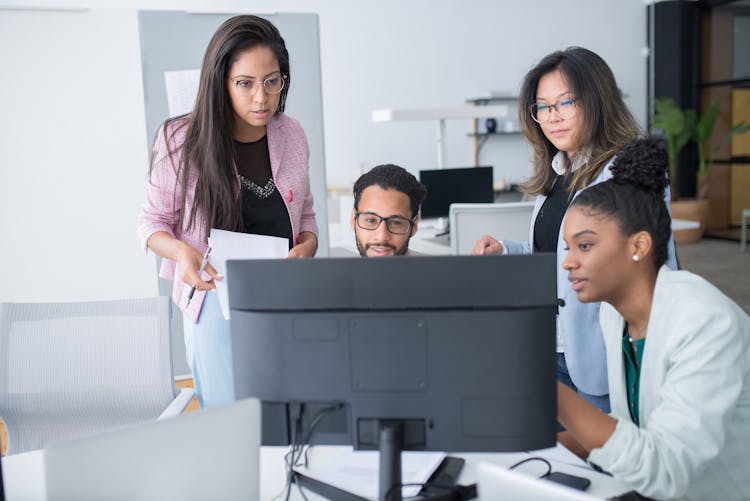 People In The Office Using A Desktop Computer For Discussion