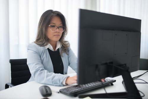 Woman Wearing a Blazer Typing on the Computer Keyboard