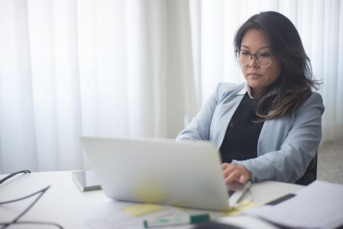 Free Focused businesswoman in office working on laptop with documents on the desk. Stock Photo