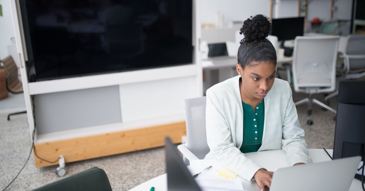 An entrepreneur in a modern UK office using a laptop to explore funding opportunities via online platforms.