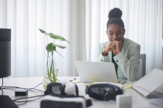 African American woman deeply focused while working on a laptop in a modern office environment.