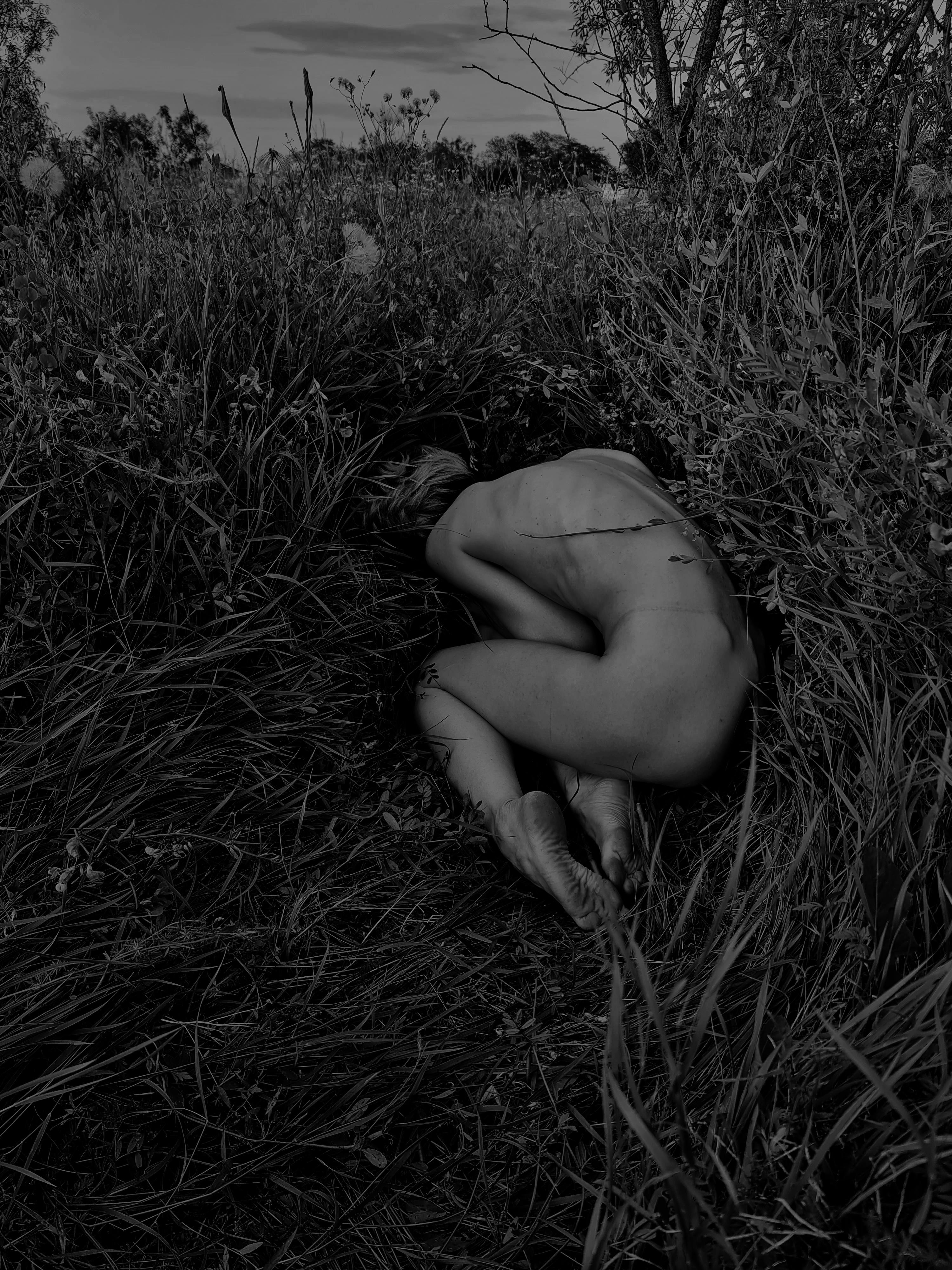 grayscale photo of a woman lying on the grass