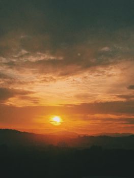 Breathtaking sunset with an orange sky and silhouetted mountains, captured during the golden hour.
